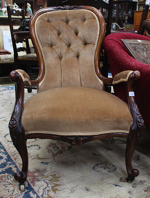 Appraisal: A VICTORIAN WALNUT OPEN ARMCHAIR with shaped overstuffed button upholstered