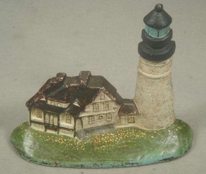 Appraisal: Cast iron doorstop tan and brown lighthouse on grassy base