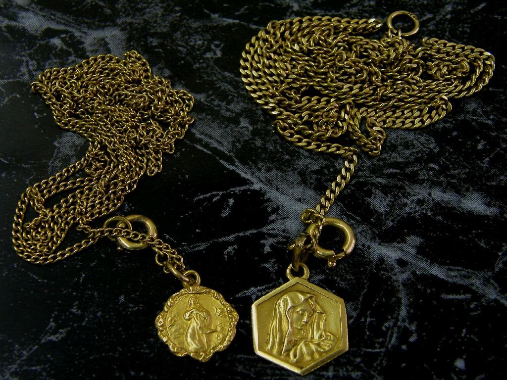 Appraisal: Two yellow metal curb necklets with two k religious pendants