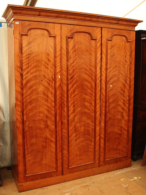 Appraisal: A VICTORIAN SATINWOOD TRIPLE WARDROBE with three panelled doors the