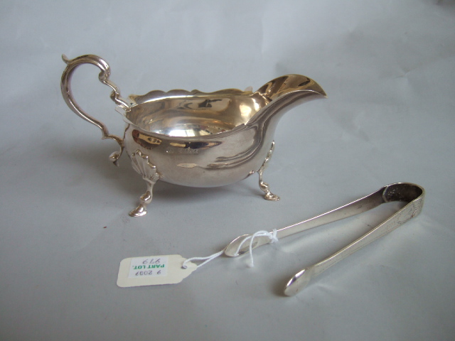 Appraisal: A silver sauceboat with a scrolling handle and shaped rim