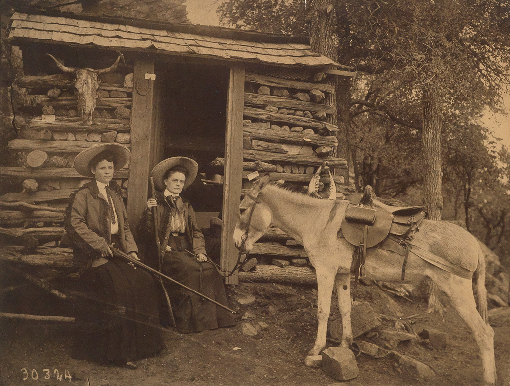 Appraisal: TEXAS Two tough broads with rifles sitting outside a cabin