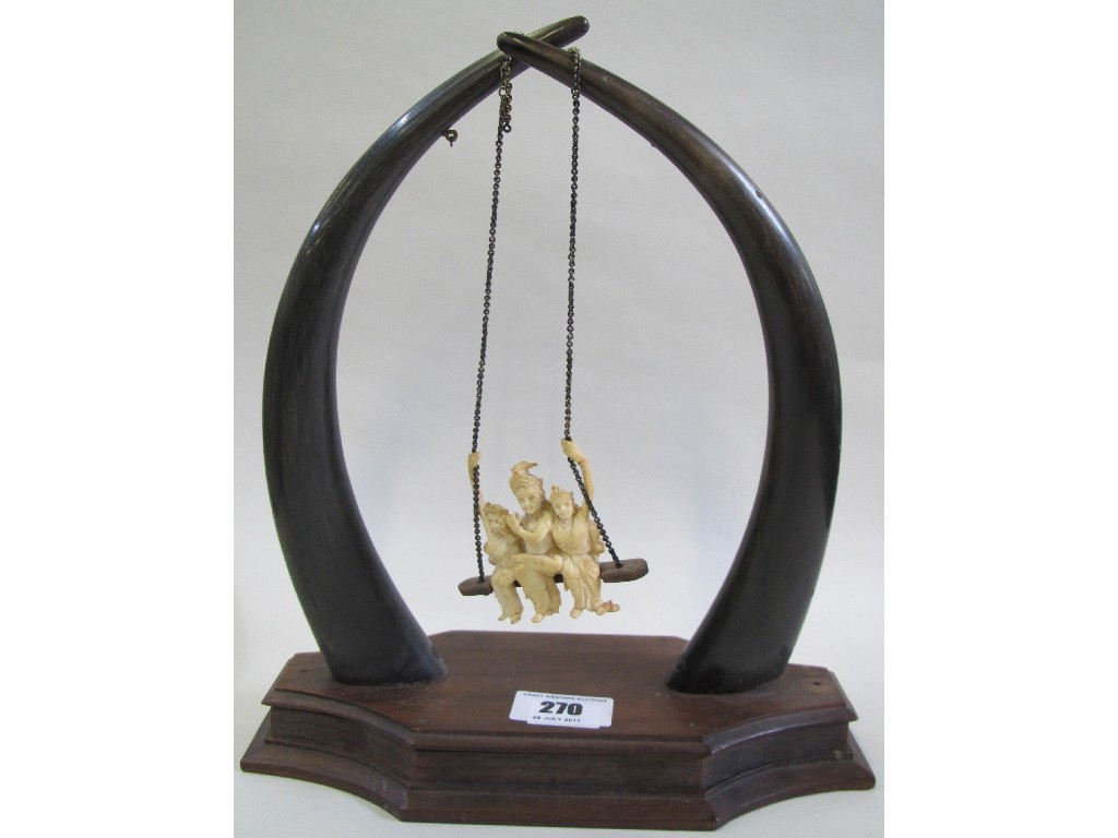 Appraisal: Carved ivory figure group on swing in horn stand