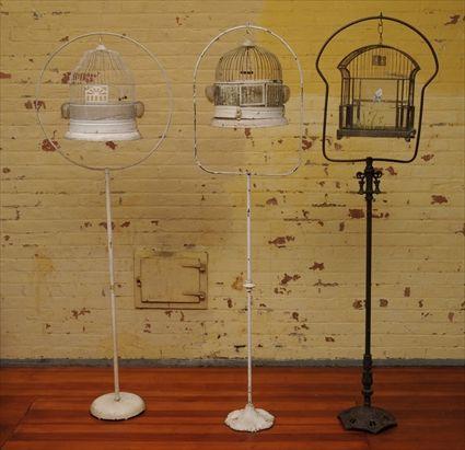 Appraisal: THREE BIRDCAGES ON STANDS One birdcage suspended from Victorian-style cast-iron