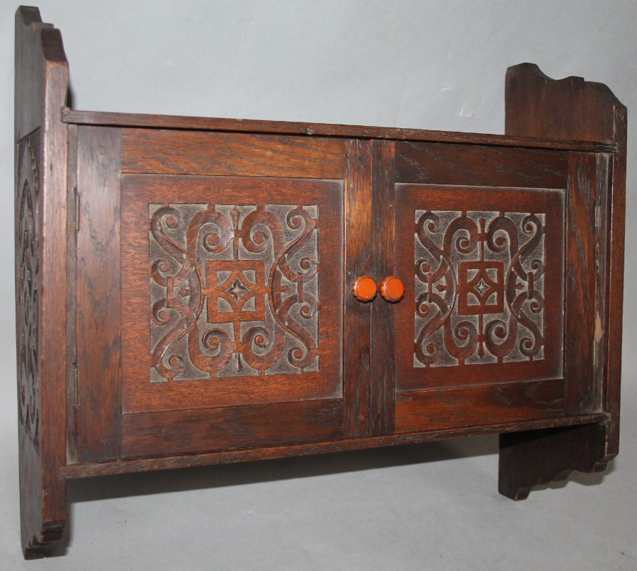 Appraisal: An Edwardian oak hanging cabinet of shaped outline centred by