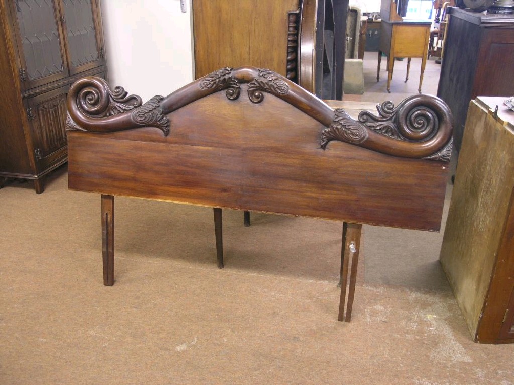 Appraisal: A Victorian mahogany headboard modified boldly carved with scrolls and