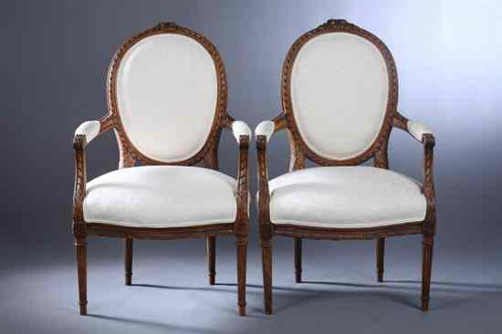 Appraisal: PAIR LOUIS XVI STYLE FRUITWOOD FAUTEUILS Carved crest ribbon-banded molding