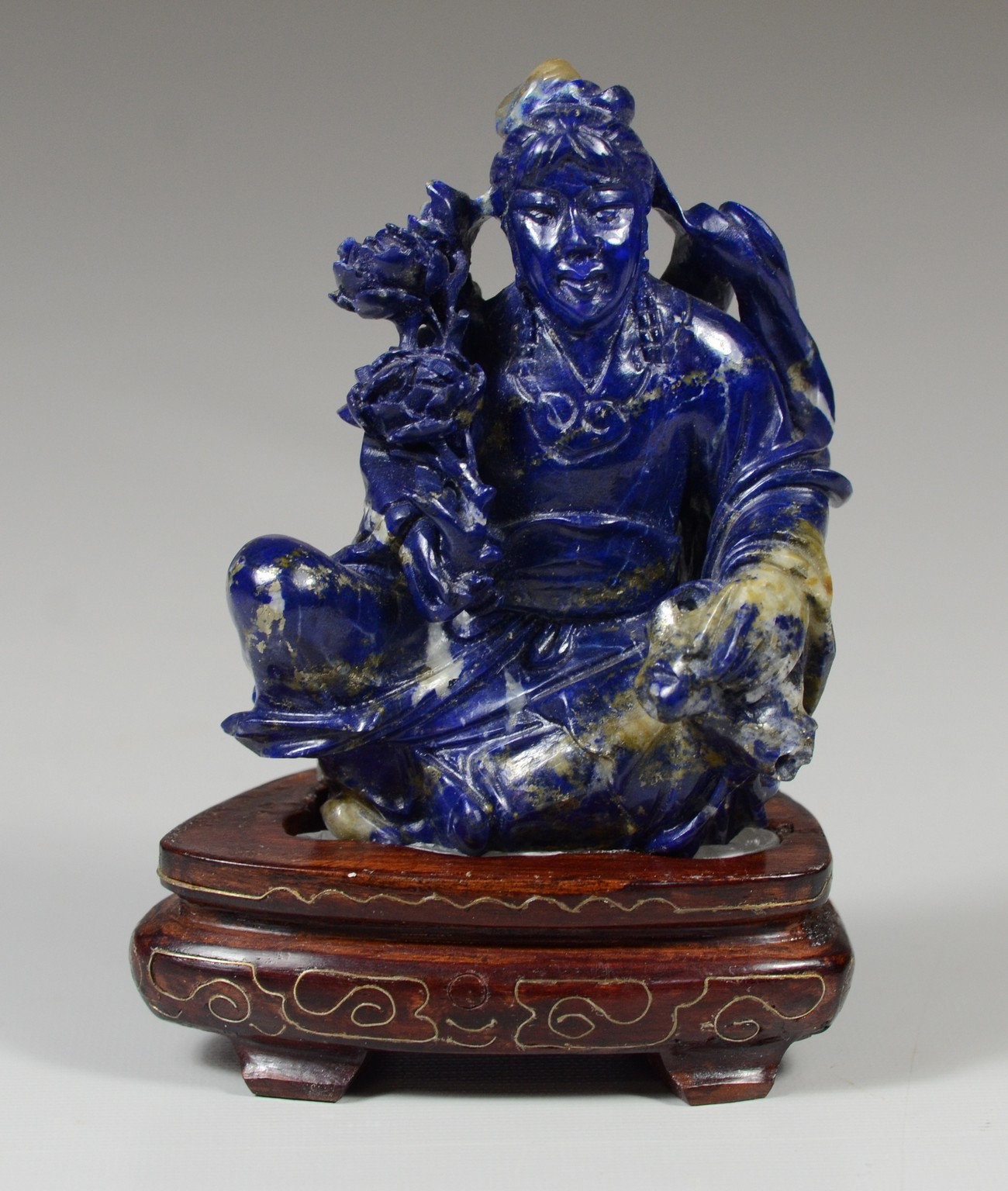 Appraisal: Carved obsidian figure of a seated man holding flowers on