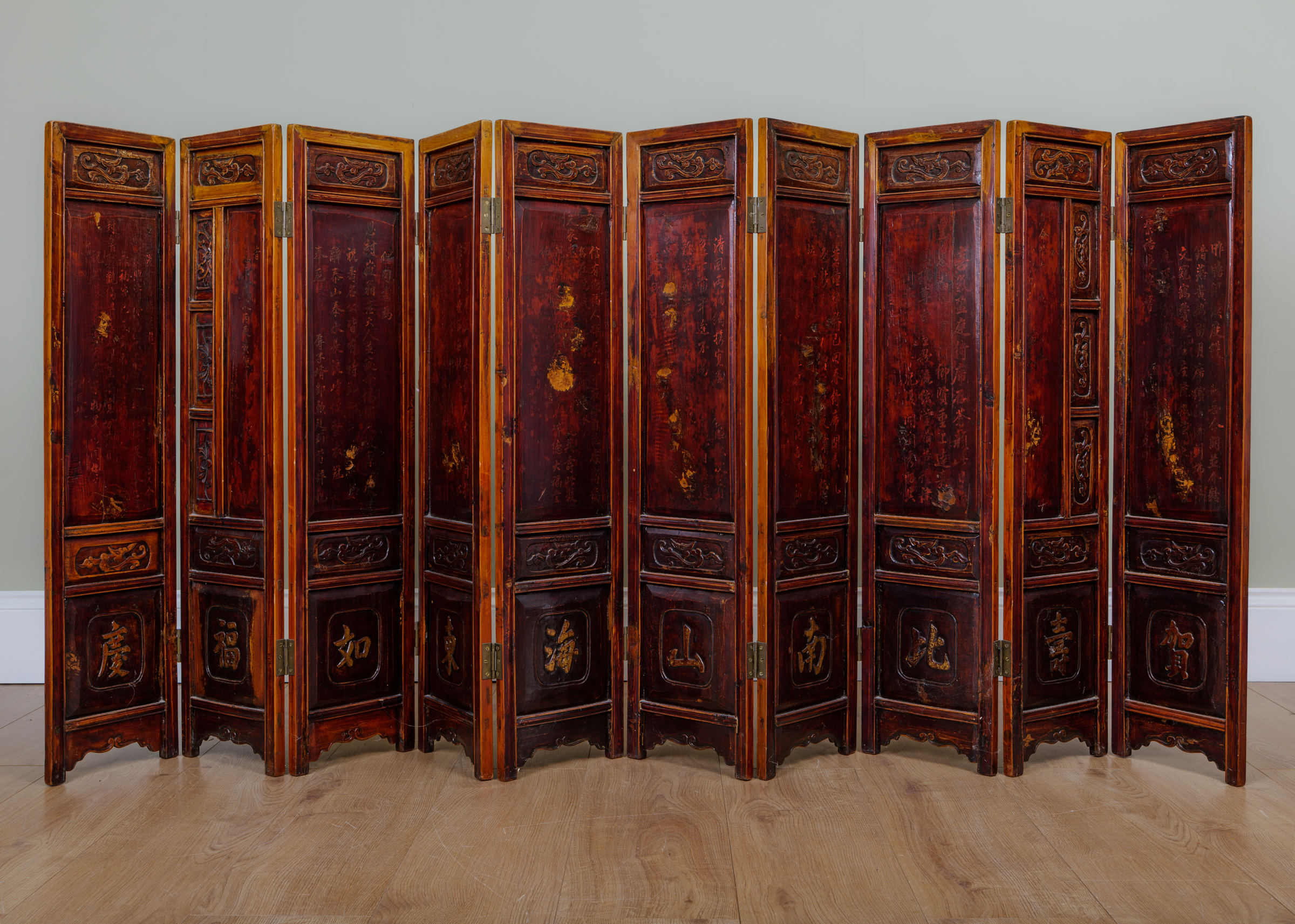 Appraisal: A Chinese tabletop lacquered softwood ten-fold screen with carved panels