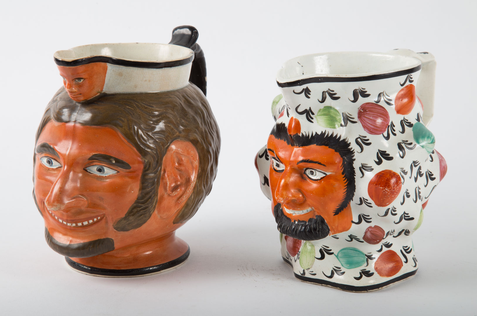 Appraisal: Two Staffordshire earthenware satyr jugs late th early th century