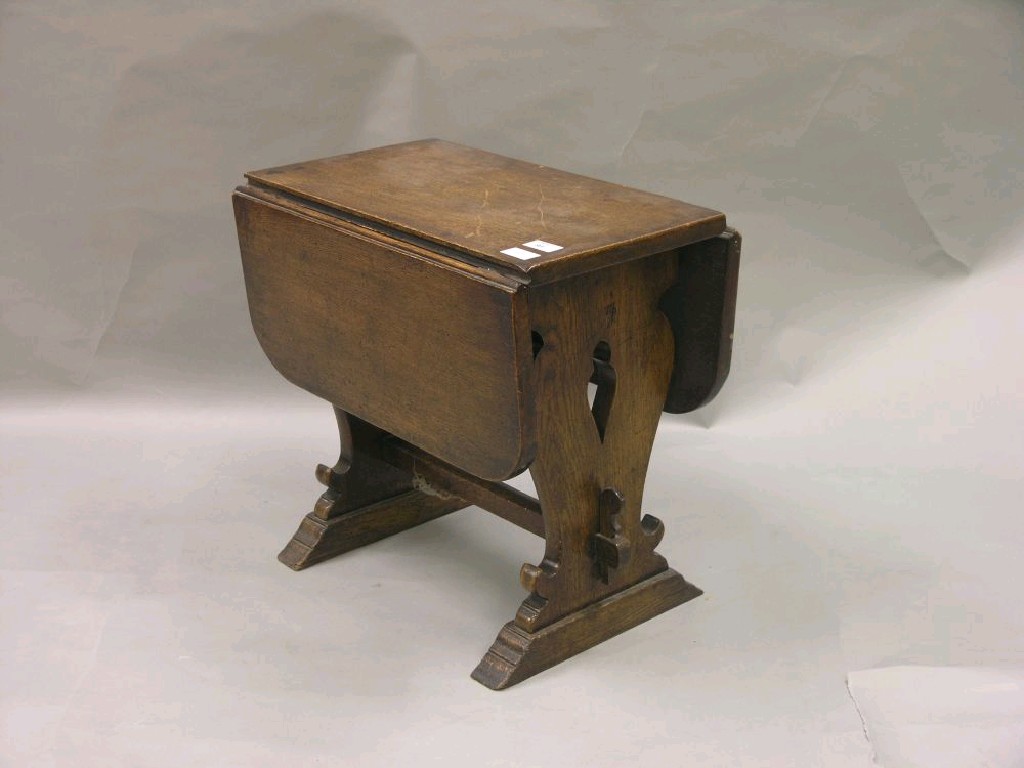 Appraisal: A solid dark oak drop-leaf coffee table on pierced end