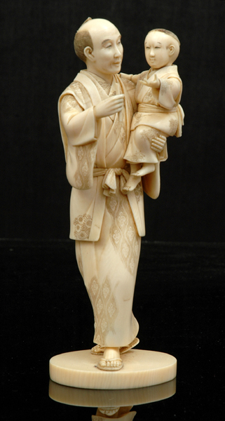 Appraisal: A JAPANESE IVORY OKIMONO OF A MAN HOLDING A BOY