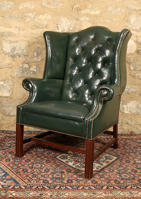 Appraisal: A GEORGIAN STYLE LEATHER UPHOLSTERED WING ARMCHAIR deep buttoned and