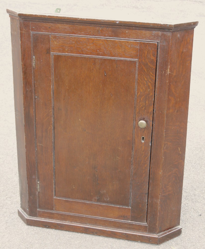 Appraisal: A George III oak hanging corner cupboard of typical outline