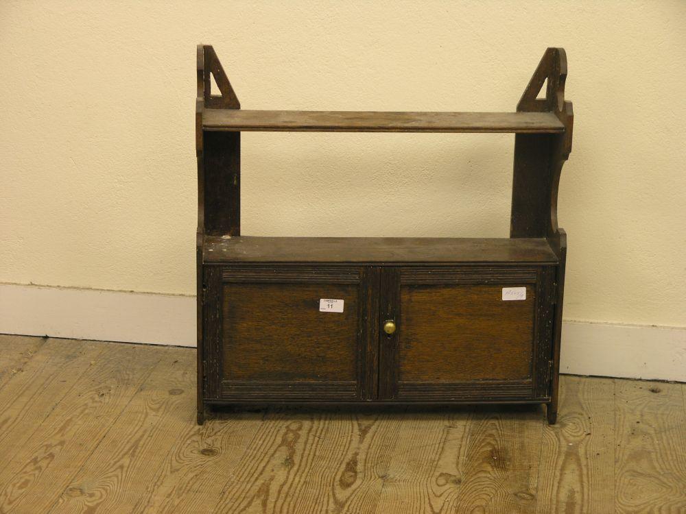 Appraisal: An oak hanging wall shelf with panelled cupboard base ft