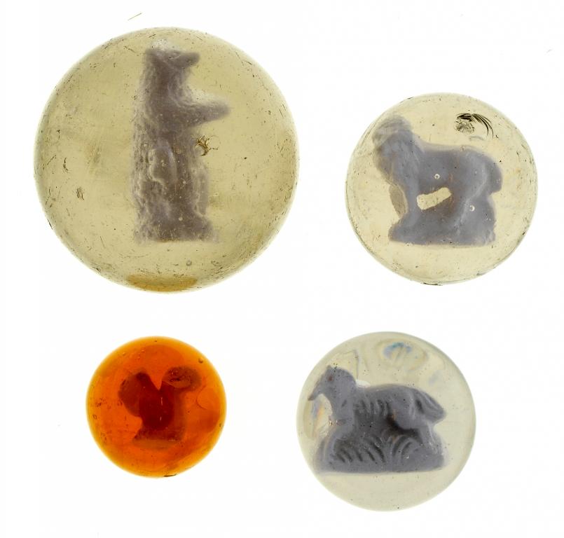 Appraisal: FOUR GLASS SULPHIDE MARBLES the smallest of amber glass the