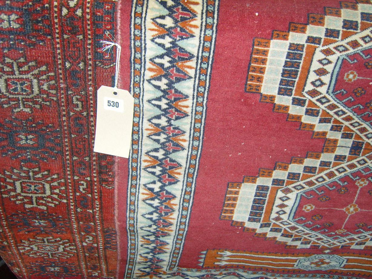 Appraisal: A red ground eastern wool rug with repeating gul decoration