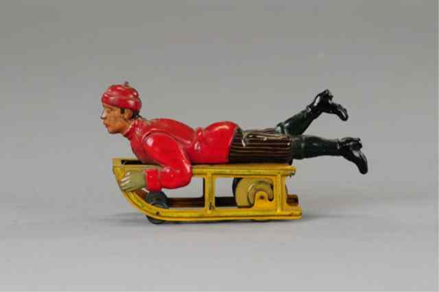 Appraisal: BOY ON SLED TOY Germany Hess lithographed tin flywheel housed