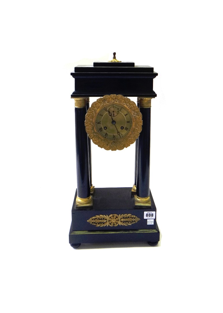 Appraisal: A French Empire ormolu mounted ebonised portico mantel clock the