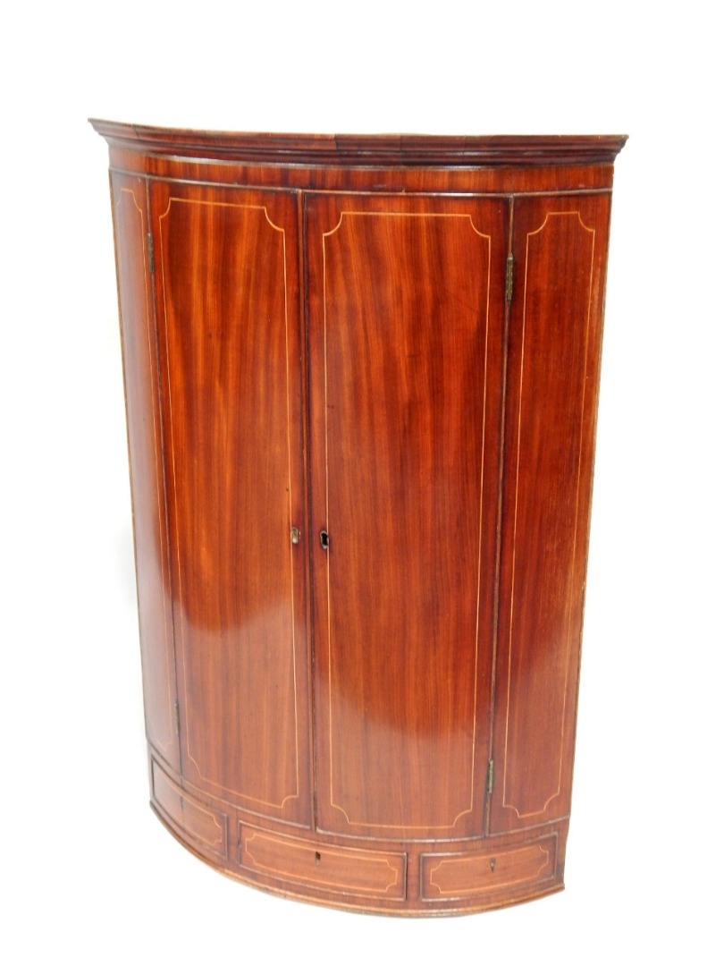 Appraisal: A Georgian mahogany barrel fronted corner cupboard with brass escutcheons