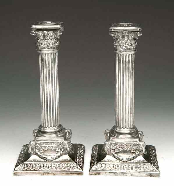 Appraisal: A PAIR OF ELECTROPLATED CANDLESTICKS with corinthian columns on stepped