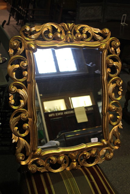 Appraisal: A CARVED GILTWOOD FRAMED WALL MIRROR with foliate scroll decoration