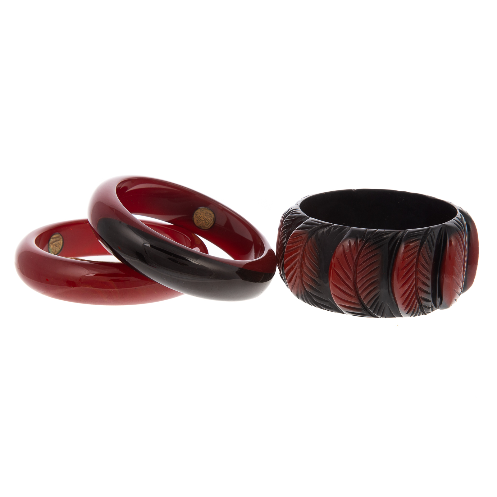 Appraisal: A TRIO OF STACKING BAKELITE BANGLES Black and red carved