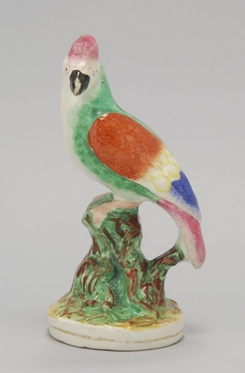 Appraisal: STAFFORDSHIRE POLYCHROME PARROT Circa Perched on a brown and green