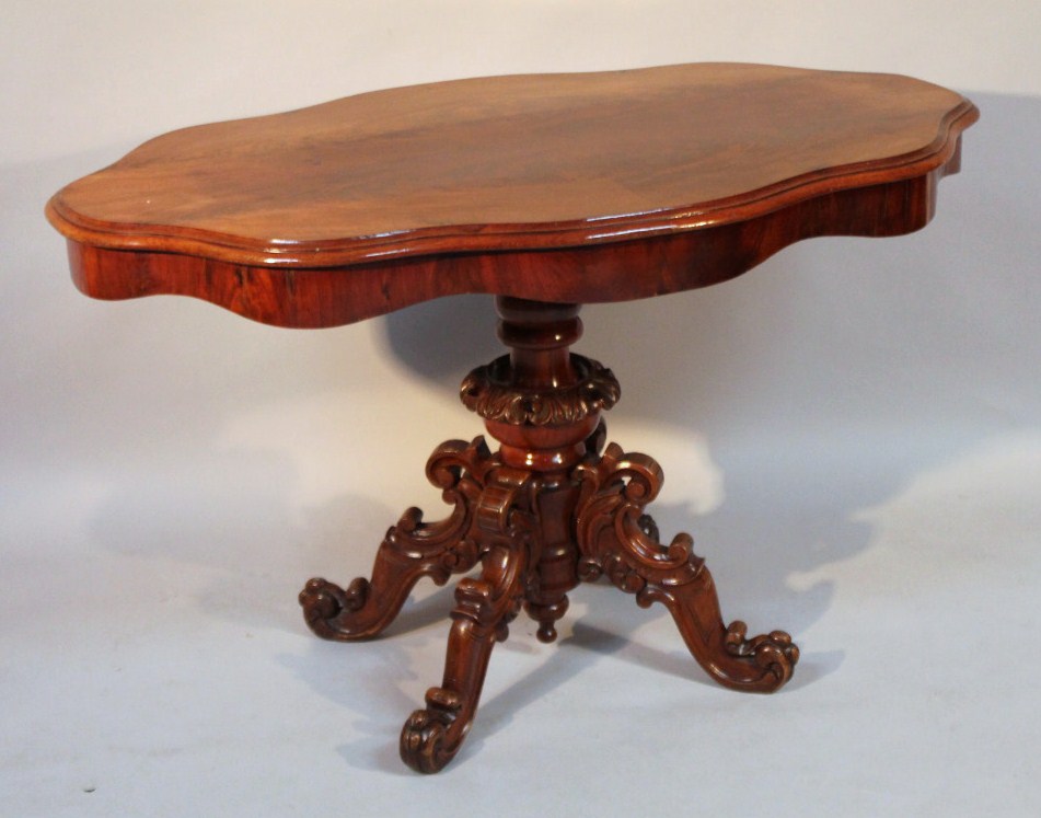 Appraisal: A flame mahogany finish occasional table with a shaped moulded