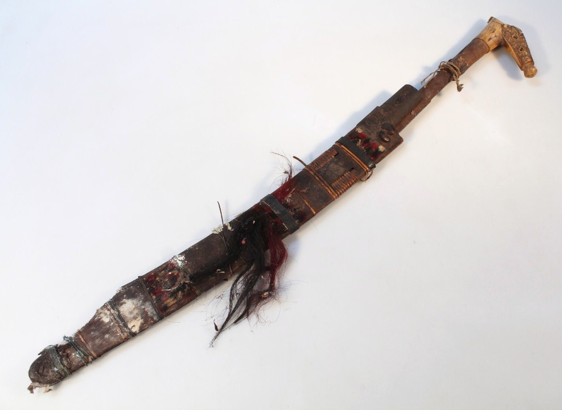 Appraisal: A thC tribal style curved dagger with wooden scabbard the