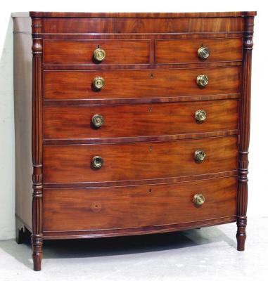 Appraisal: A REGENCY MAHOGANY CHEST of bowed form with protruding turned