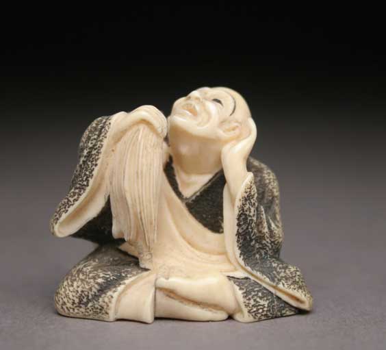 Appraisal: CARVED IVORY NETSUKE Triangular carved ivory netsuke of a man