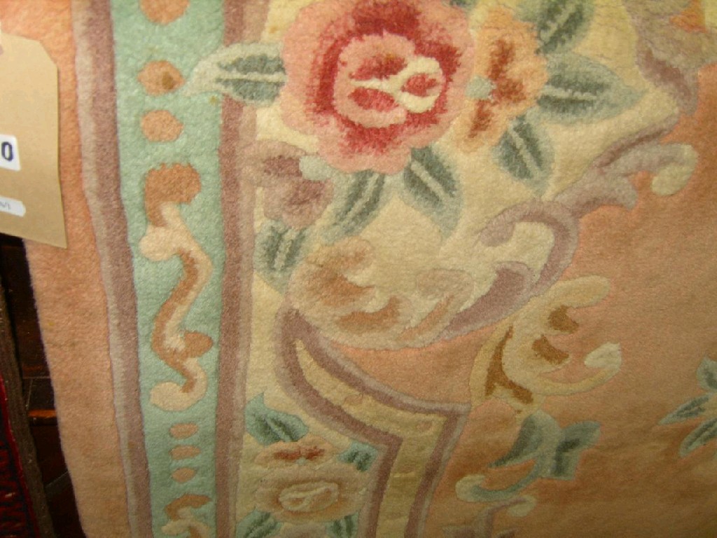 Appraisal: A Chinese peach ground wool rug with floral medallion and