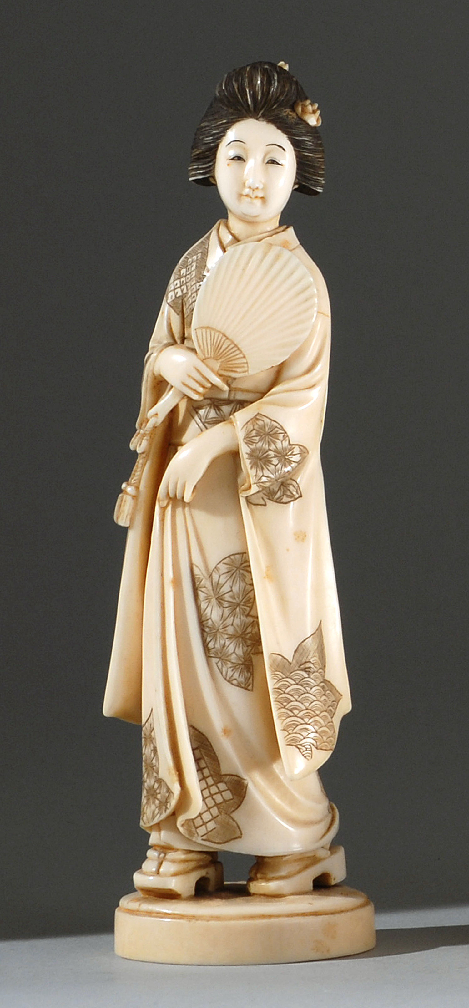 Appraisal: IVORY FIGURE OF A MAIDEN Meiji PeriodDepicted walking while holding