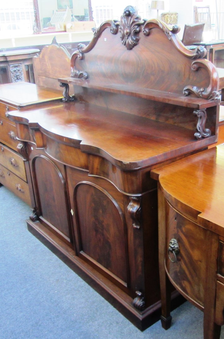 Appraisal: A Victorian mahogany ledge back serpentine sideboard on plinth base