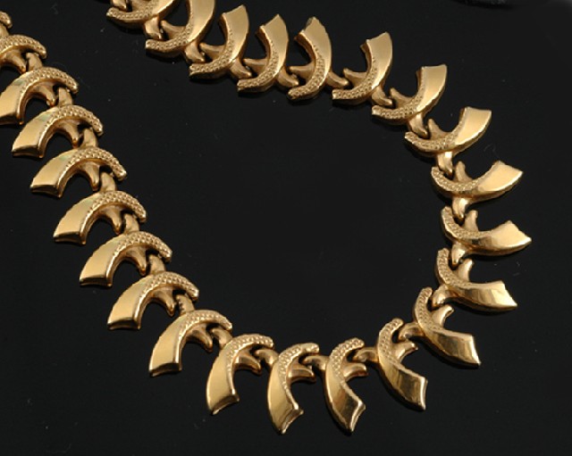 Appraisal: A gold fringed necklace Having articulated curved links with engraved