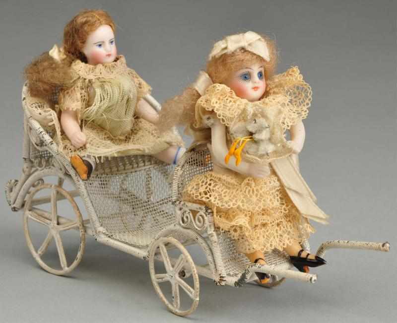 Appraisal: Pair of All Bisque Dolls in Stroller Description Larger is