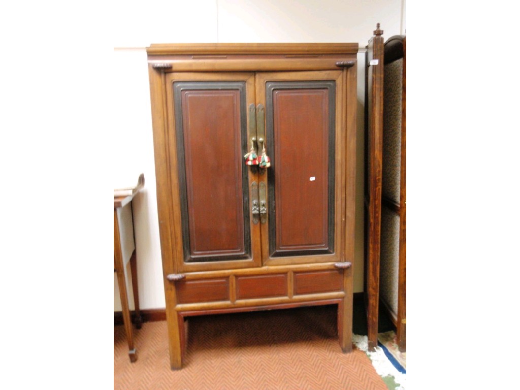 Appraisal: A thC Chinese cabinet enclosed by two panelled doors raised