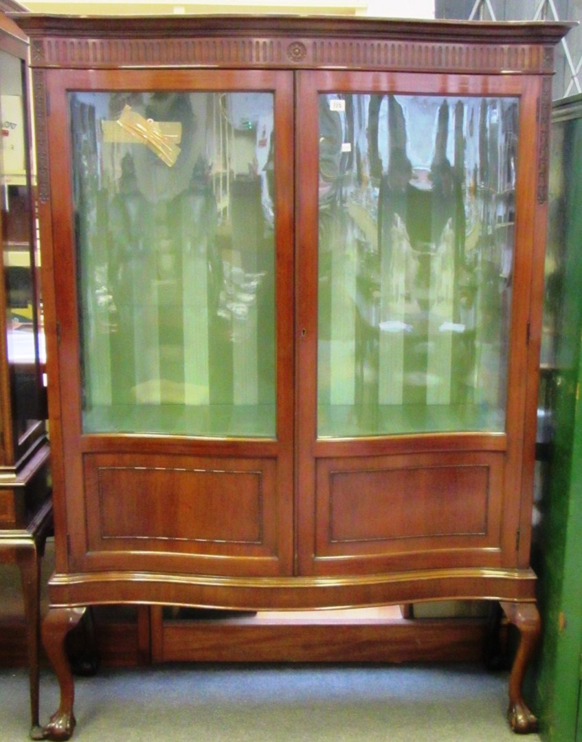 Appraisal: An Edwardian mahogany serpentine two door display cabinet on claw