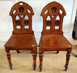 Appraisal: A pair of Victorian oak hall chairs in the Gothic