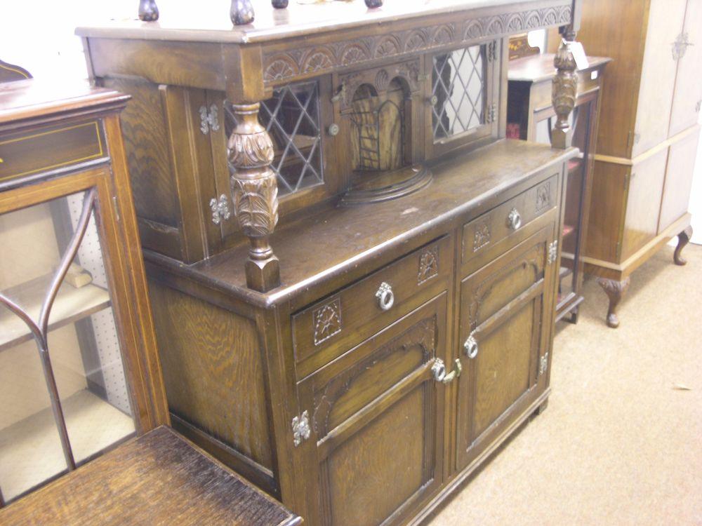 Appraisal: A reproduction dark oak court cupboard with carved lunette rail