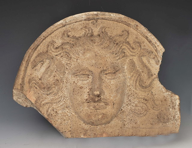 Appraisal: A GREEK POTTERY MEDUSA HEAD PLAQUE FRAGMENT with domed top