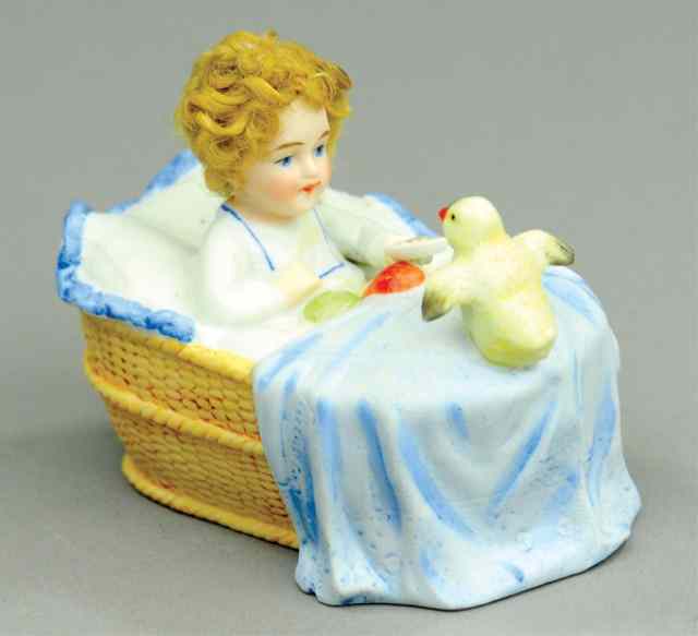 Appraisal: GIRL FEEDING BIRD IN CRADLE STILL BANK Porcelain a very