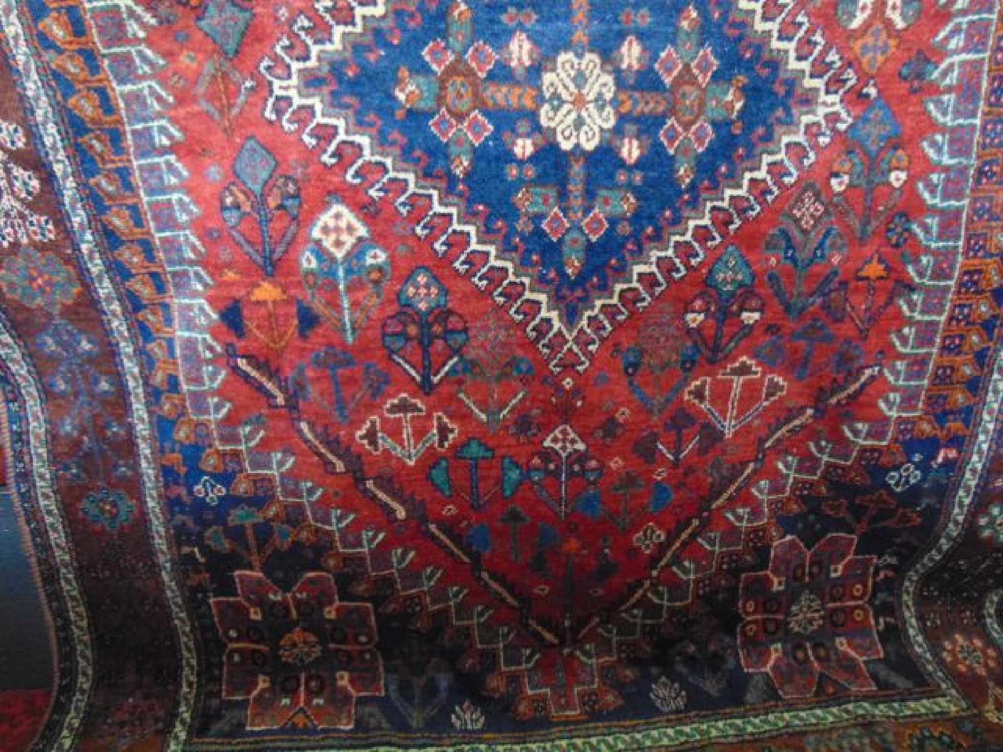 Appraisal: A Persian wool rug with red ground field blue ground