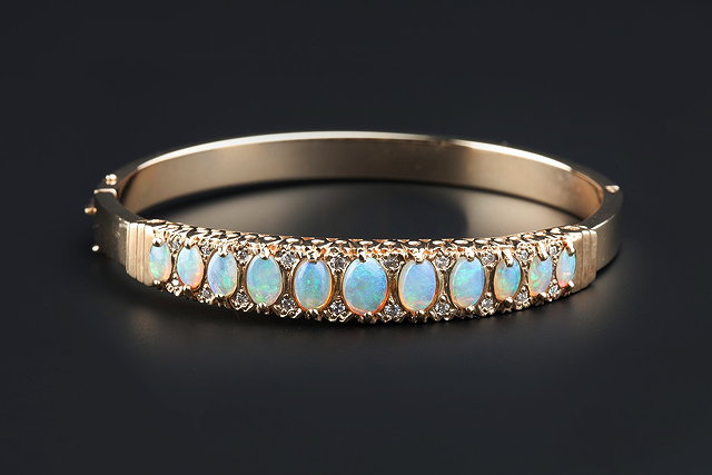 Appraisal: AN OPAL AND DIAMOND SET BANGLE of hinged oval form