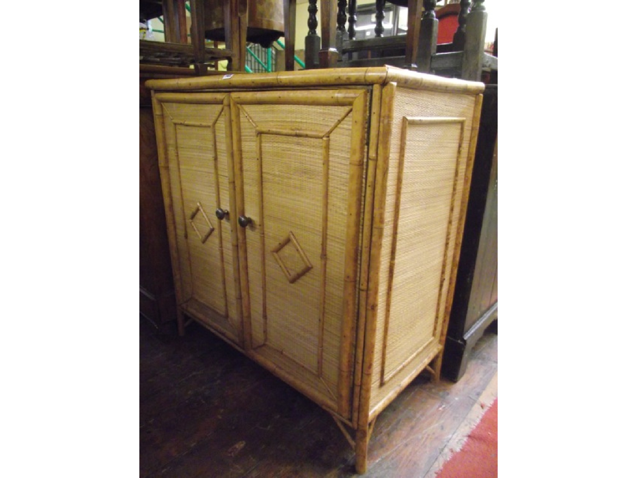 Appraisal: A bamboo side cupboard enclosed by a two panelled door