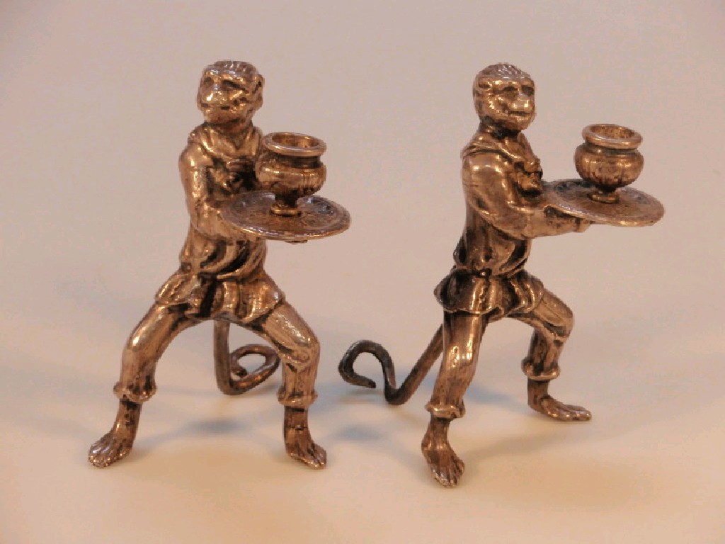 Appraisal: A pair of white metal monkey candlesticks modelled as standing