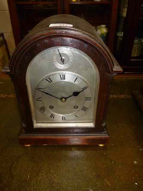 Appraisal: AN OAK MANTEL CLOCK the arching case and fluted chamfered