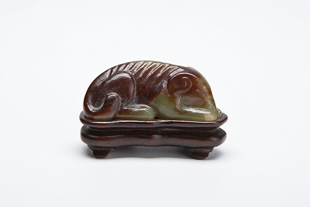 Appraisal: A CHINESE BROWN AND PALE GREEN JADE RECUMBENT HOUND its