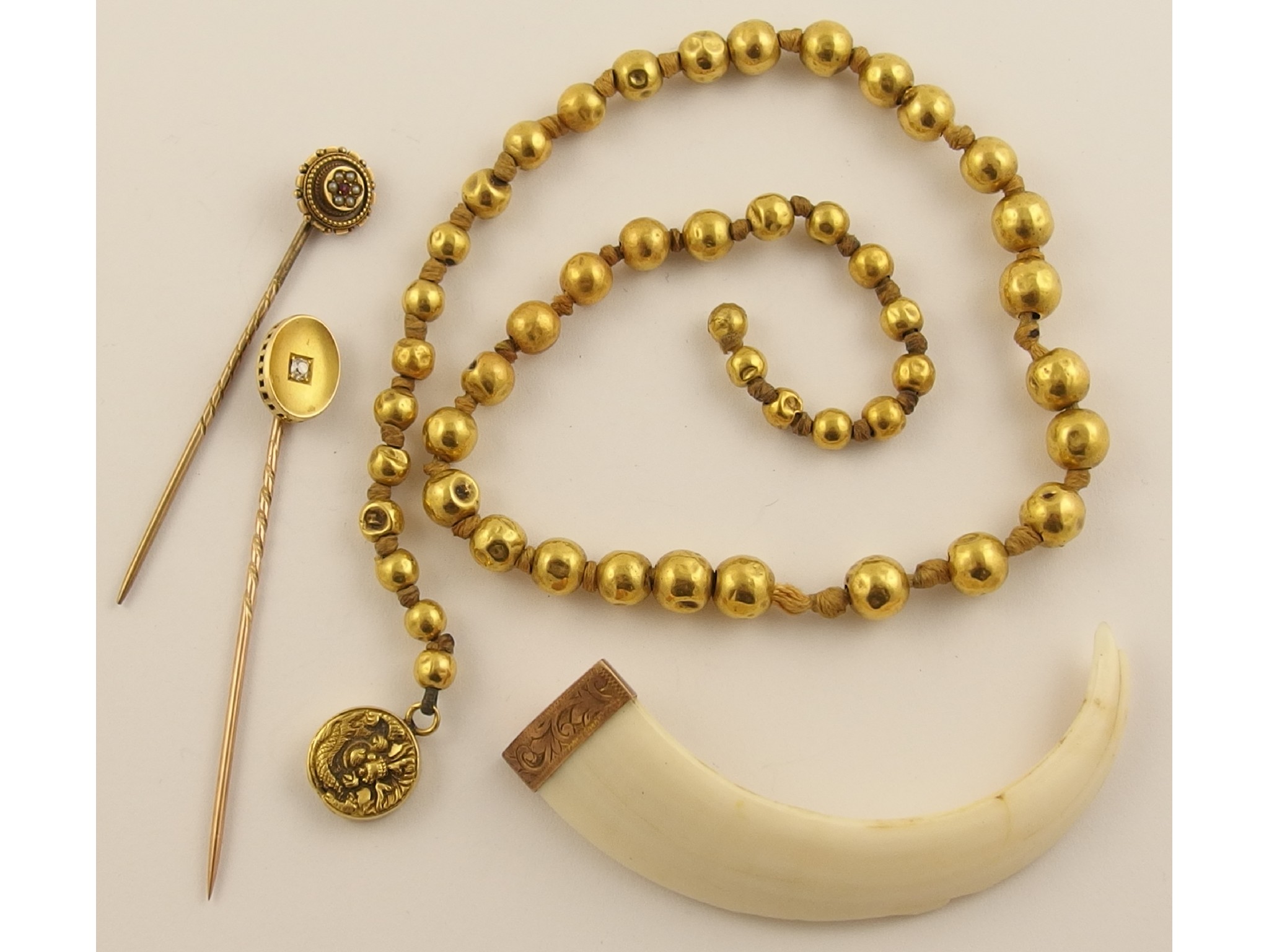 Appraisal: A yellow metal bead necklace with a Chinese dragon clasp